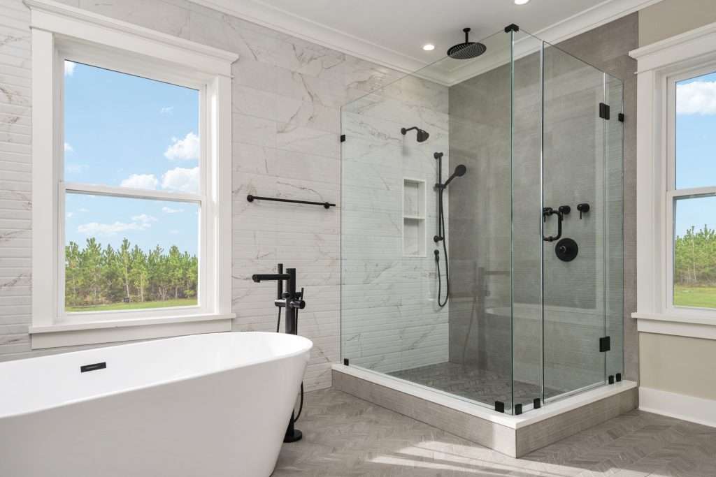 Custom moodernized bathroom remodel featuring stone-accented shower, tub, toilet, and faucet.