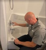 The Werrlein Companies repair person services the faucet in a bathtub